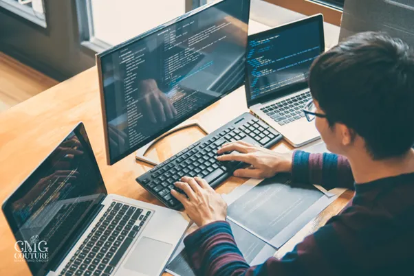 A man working intently on his laptop and desktop, illustrating the process of web development
